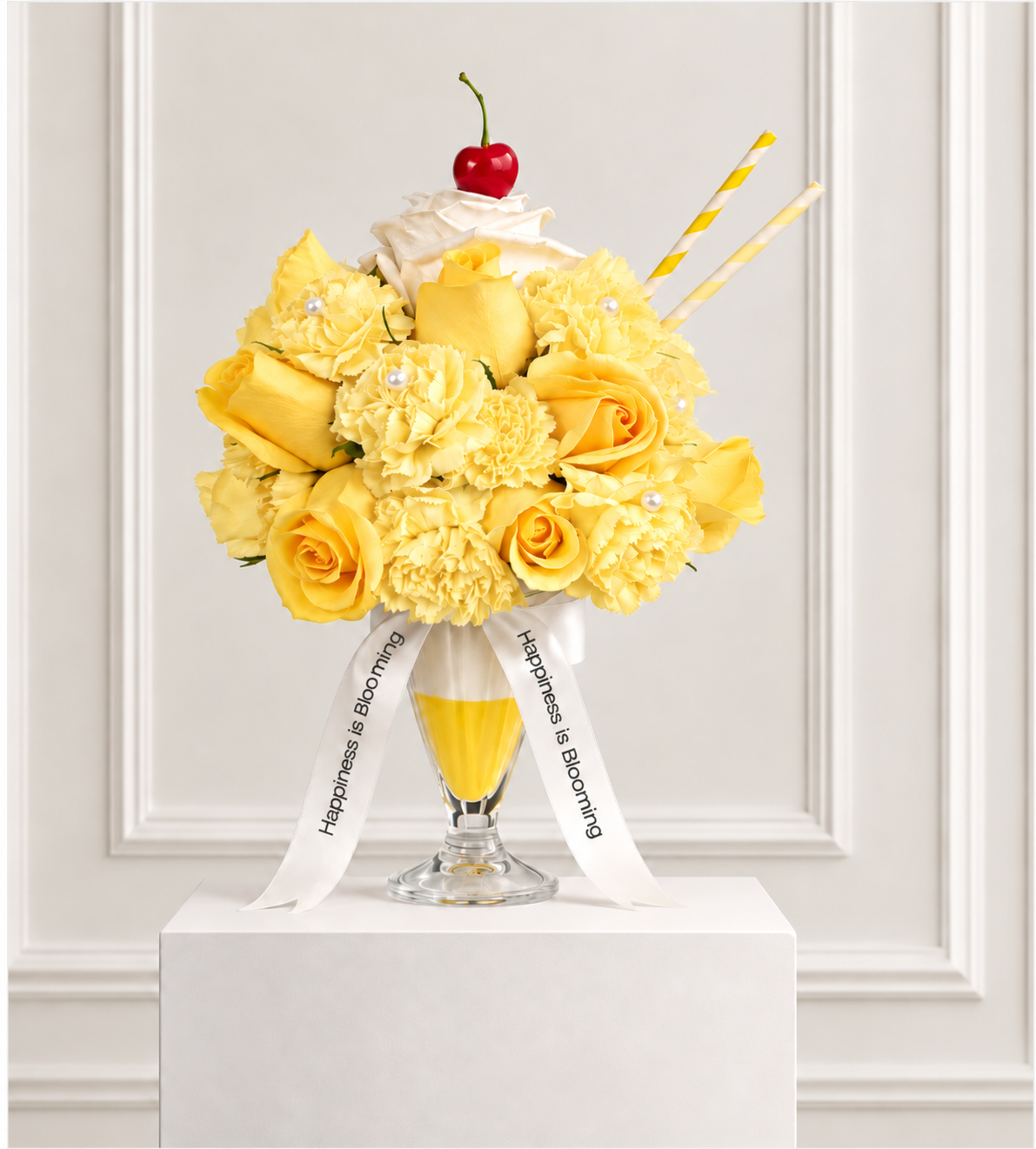 Le Soleil flower frappé: yellow roses and carnations with faux pearls in a sundae glass, topped with a white rose whipped cream and a cherry, with striped straws and Happiness is Blooming ribbons